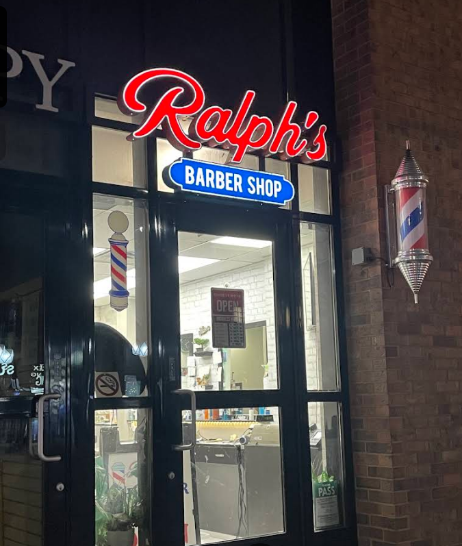 Ralph's Barber Shop storefront at night, lit sign and barber pole